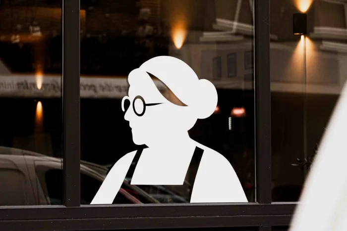 Silhouette du pizzaiolo détourée sur la vitrine le soir, rue éclairée en arrière-plan à La Louvière